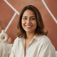 Portrait of a smiling South Asian woman in her 30s, looking at the camera with a friendly expression.